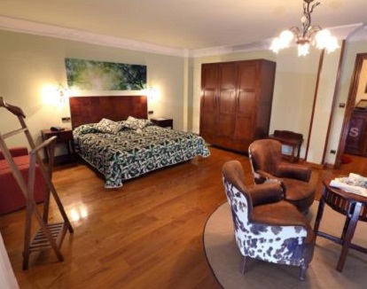 Foto del interior de la Habitación con cama extragrande y bañera de hidromasaje donde se puede ver que se trata de una habitacion muy grande, con suelos de madera