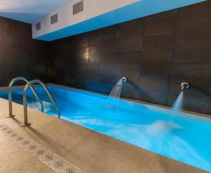 Piscina cubierta con elementos de hidroterapia del spa del hotel.