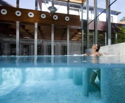 Mujer disfrutando de la piscina cubierta del centro de spa del hotel.