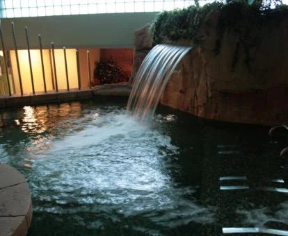 Fabulosa piscina interior con cascada del spa del hotel.