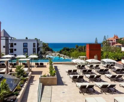 Zonas exteriores con piscina y tumbonas de este hotel con vistas al mar.