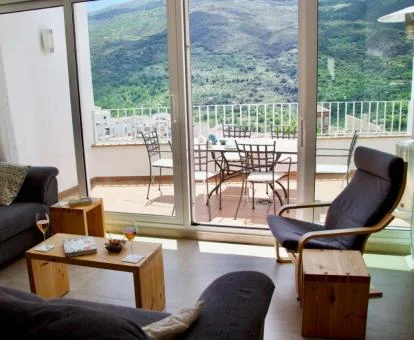 Sala de estar con amplios ventanales y vistas a las montañas de esta coqueta casa.