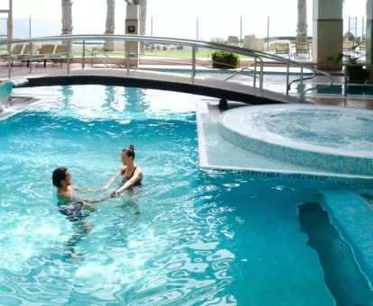 Pareja disfrutando de la fabulosa piscina de hidroterapia del spa con vistas al exterior.