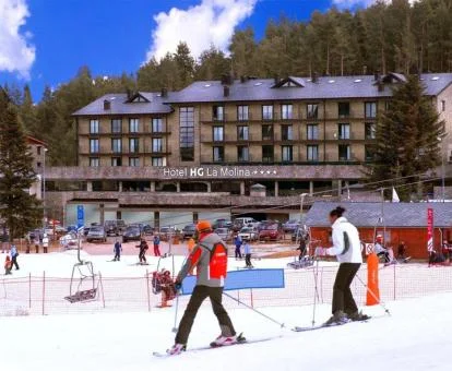 Varias personas disfrutan de las pistas de esquí junto a este hermoso hotel de montaña.