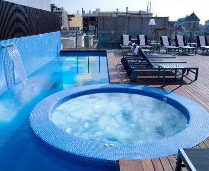 Jacuzzi circular funcionando y piscina con cascada en la terraza de la azotea del hotel.