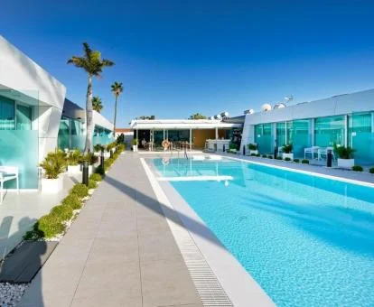 Amplia piscina exterior rodeada de habitaciones con terraza privada.