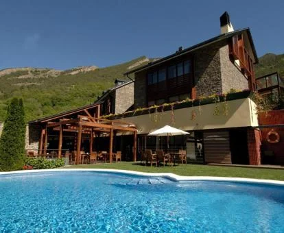 Bello hotel de montaña rodeado de naturaleza con piscina exterior.