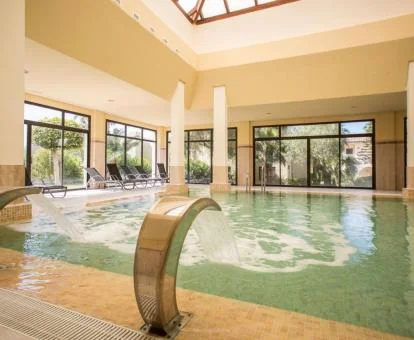 Piscina cubierta con hidroterapia y vistas al exterior del centro de bienestar del hotel.