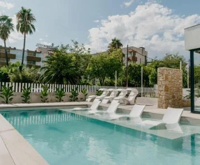 Coqueta zona exterior con piscina con tumbonas en el agua de este hotel con encanto.