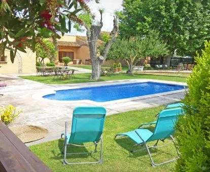 Bella zona exterior ajardinada con vegetación y piscina de esta masía rural.
