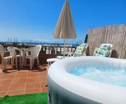 Terraza privada con mobiliario, jacuzzi privado y vistas al mar de este ático.