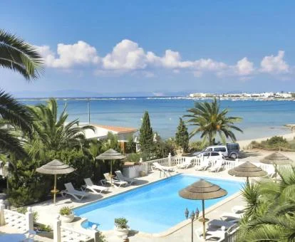 Preciosa zona exterior con piscina y vistas al mar rodeada de vegetación.