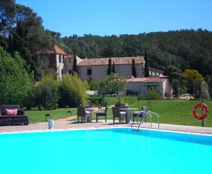 Hotel rural rodeado de vegetación con amplios jardines y piscina exterior.