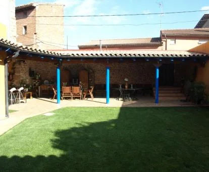 Zona exterior ajardinada de este alojamiento solo para adultos con porche y mobiliario.