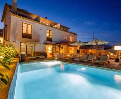 Hotel con encanto con piscina exterior y bella iluminación nocturna.