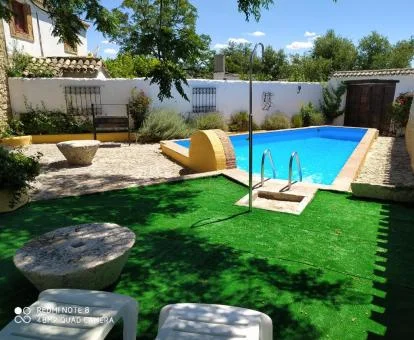 Zona exterior ajardinada con piscina de este cortijo rural.