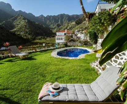 Amplio jardín con piscina exterior de este complejo de apartamentos rodeado de montañas.