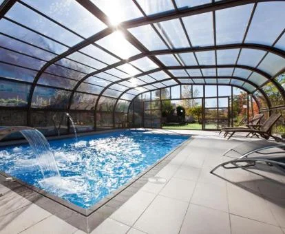 Piscina cubierta con hidroterapia y cristaleras con vistas al exterior.