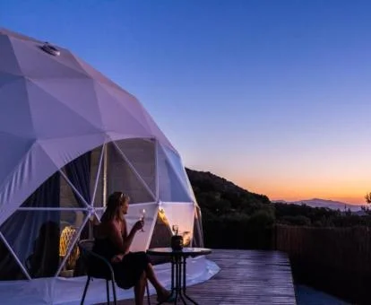 Mujer disfrutando del atardecer en la terraza de esta habitación burbuja con espectaculares vistas.