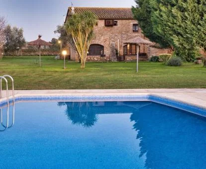 Piscina exterior con amplios jardines y, detrás, la fachada del hotel.