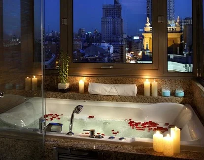 Foto del Jacuzzi privado con vistas a la ciudad de Madrid con un toque romántico con las velas y los petalos en el agua