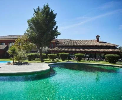 Hermoso hotel boutique con una gran piscina exterior rodeada de jardines.