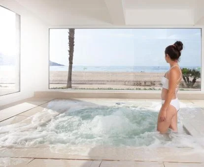 Mujer disfrutando de la zona de aguas con vistas al mar del spa.