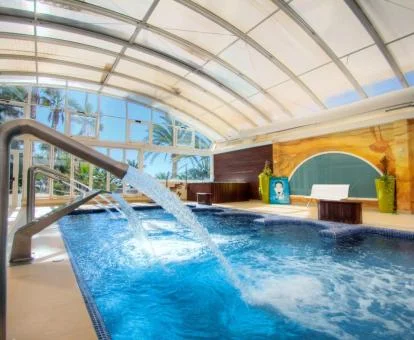 Piscina cubierta con hidroterapia y vistas al exterior del spa.
