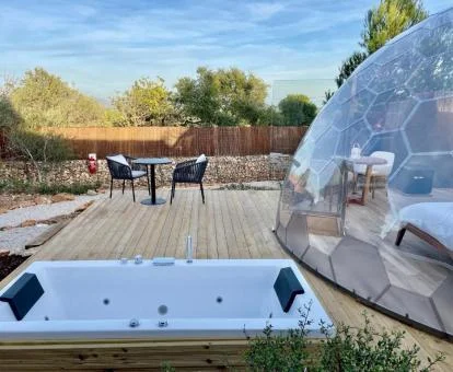 Zona exterior privada con jacuzzi y mobiliario de una de las burbujas de este establecimiento rural.