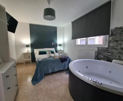 Dormitorio con bañera de hidromasaje privada junto a la cama de esta preciosa suite deluxe.