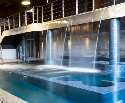 Fabulosa piscina interior con cascadas del spa del hotel.
