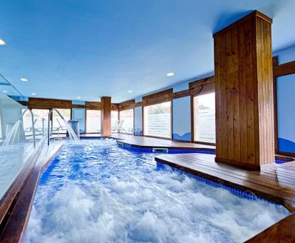 Piscina cubierta con hidroterapia y vistas al exterior del centro de bienestar del hotel.
