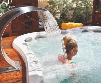 Mujer disfrutando del jacuzzi con cuello de cascada del spa.
