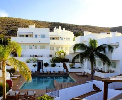 Hotel rural con piscina exterior rodeado de montañas.