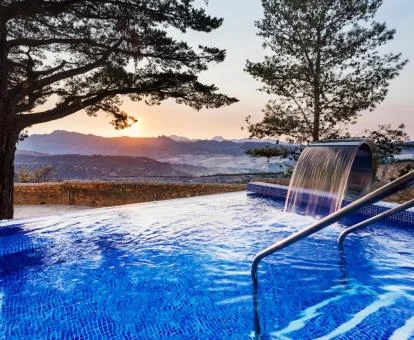 Piscina exterior con chorro en cascada y vistas a la naturaleza de este hotel con encanto.