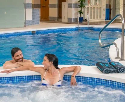 Pareja disfrutando de la piscina de hidroterapia del spa.