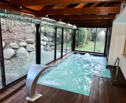 Piscina cubierta con chorros de hidroterapia y vistas al jardín del spa del hotel.