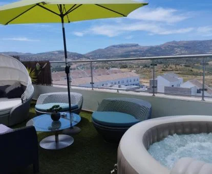 Terraza amueblada con jacuzzi privado exterior del apartamento con vistas a las montañas.