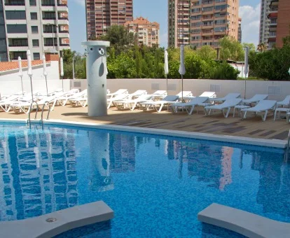 Piscina exterior de este hotel de ciudad con solarium y tumbonas.
