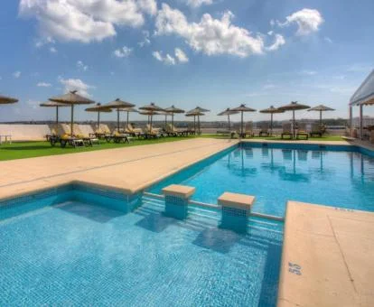 Piscinas exteriores rodeadas de tumbonas.