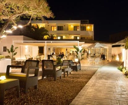 Precioso hotel con terraza y comedores exteriores con iluminación nocturna.