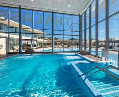 Piscina cubierta acristalada con vistas al exterior del spa del hotel.