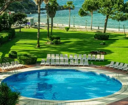 Piscina exterior de este hotel con encanto rodeada de jardines que dan acceso a la playa.