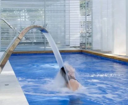 Mujer disfrutando de los chorros de hidroterapia de la piscina del hotel.