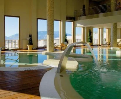 Piscina interior con hidroterapia y vistas a la naturaleza del spa del hotel.