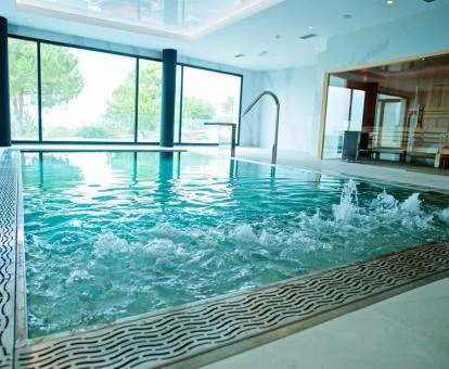 Gran piscina de hidroterapia con grandes ventanales y vistas del spa del hotel.