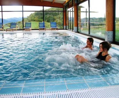 Pareja disfrutando de la piscina con elementos de hidroterapia del spa con espectaculares vistas a la naturaleza.