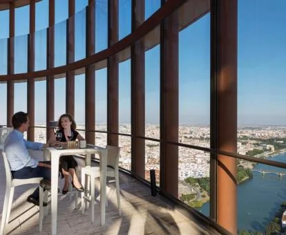 Pareja disfrutando de un aperitivo en el comedor con espectaculares vistas a la ciudad de este hotel.