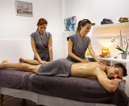 Hombre disfrutando de un relajante masaje a cuatro manos en la sala de bienestar del hotel.