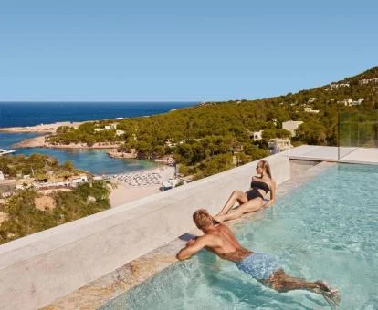 Pareja disfrutando de la piscina con vistas al mar de este hotel romántico.